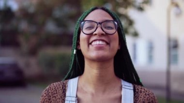 Dışarıda kameraya gülümseyen mutlu bir genç siyahi kadın. Süslü saçları olan Brezilyalı yetişkin bir kız..