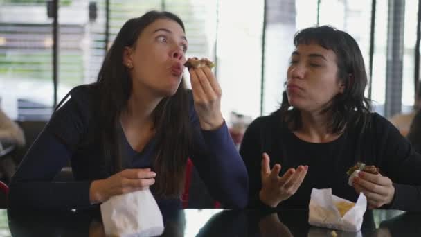 Две Латиноамериканские Латиноамериканки Едят Фаст Фуд Обед Девушки Едят Бургеры — стоковое видео