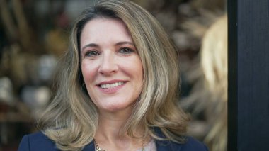 Orta yaşlı bir girişimcinin portresi. Küçük yerel bir atölyenin önünde kameraya bakıyor.