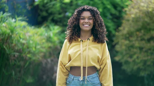 巻き毛と黄色のブラウスが屋外に立っている1つのトレンディーな幸せなアフリカ系アメリカ人の女の子 笑顔黒ヒスパニックラティーナ20代女性で垂直ビデオ — ストック写真
