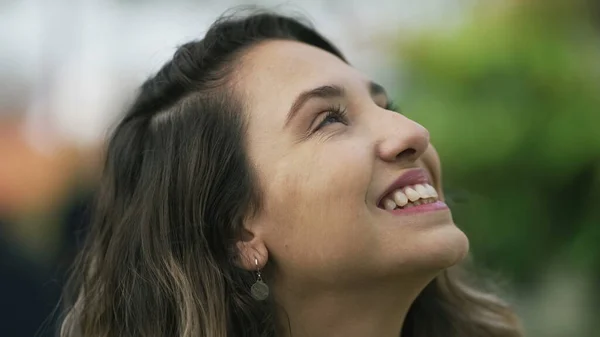 Happy woman closeup face looking up at sky smiling. One hopeful hispanic 20s adult girl