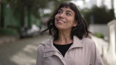 Kameraya doğru yürüyen mutlu bir İspanyol genç kadın. Kaygısız, gülümseyen Güney Amerikalı bir Latin kız dışarı çıkıyor. Özgür insan yürüyüşü.