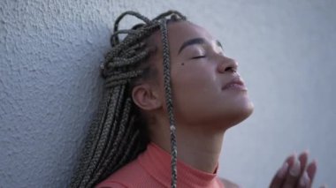 Ruhani bir genç siyahi kadın Tanrı 'ya yardım ve destek için dua ediyor. Sadık bir Brezilyalı yetişkin kız gökyüzüne umutla ve inançla bakıyor