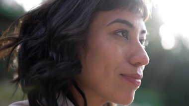 Gökyüzüne gülümseyen kadın yüzünü kapat. Güney Amerikalı özgüvenli bir kızın profili güneş ışığında dışarıda duruyor..