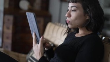 Genç İspanyol kadın, tableti çevrimiçi içerikte okunmaya ve kaydırılmaya yaklaştırıyor