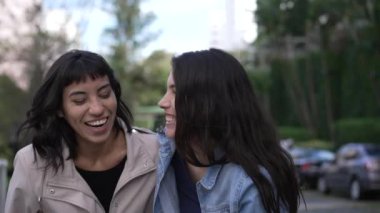 Two female friends laughing and smiling together pointing at funny reaction.