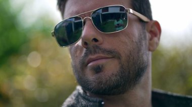Dışarıda güneş gözlüğü takan yakışıklı bir genç. Gözlüklü bir erkeğin yakın çekim yüzü.