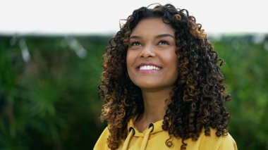 Mutlu Afrika kökenli Amerikalı kadın gökyüzüne bakıp gülümsüyor. Umutlu bir siyah Latin 20 'li yaşlarda yetişkin bir kız.