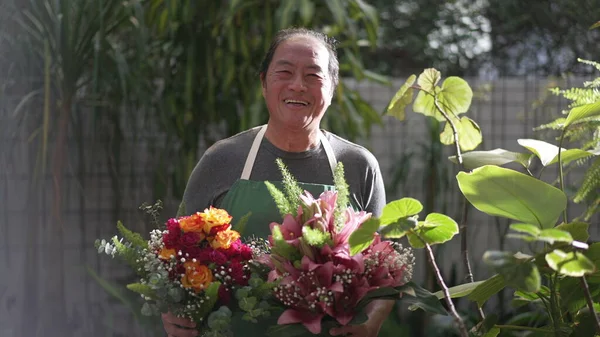 Florist entrepreneur holding bouquet of flower arrangement ready for customer delivery. Male Asian middle age entrepreneur carries colorful roses