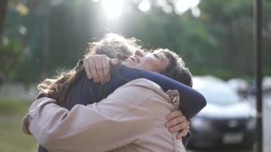 Two happy female best friends hugging each other. Women embrace reunion outdoors at park