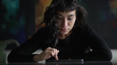 Tablet kullanan bir kadın. Güney Amerikalı Latin kız ekrandaki modern dijital teknolojiye bakıyor. İnternette gezinen kişi