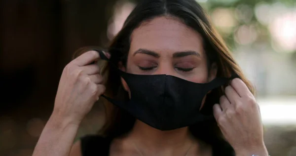 Latin woman removing covid face mask end of pandemic