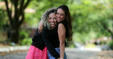 Parkta sarılıp kucaklaşan iki mutlu bayan arkadaş.