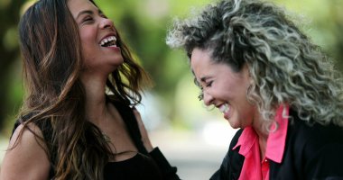 İnternetteki medya içeriğine gülen ve gülümseyen iki arkadaş, komik bir mesaj.