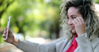 Bir kadın telefon kamerasıyla kendi dışından selfie çekiyor.