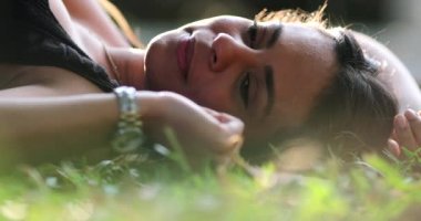 Genç İspanyol kadın dışarıda çim parkında dinleniyor.