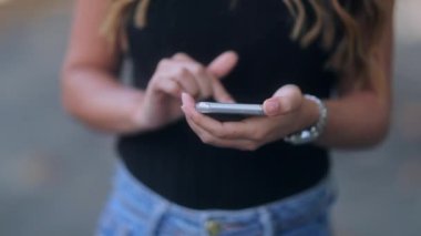 İspanyol kadın dışarıda akıllı telefon cihazıyla internette geziniyor.