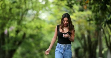 Güzel kız telefondaki mesajla mutlu. Sevinçten zıplıyor.