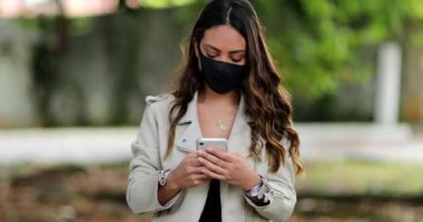 Kapalı maskeli bir kişi dışarıda cep telefonu kullanıyor.