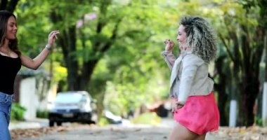 Mutlu insanlar sokakta dans eder, iki bayan arkadaş hayatı dans ederek kutlar.