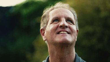 Minnettar, olgun bir adam gökyüzüne umutla gülümsüyor. Sadık bir kıdemli dışarıda minnettarlıkla bekliyor.