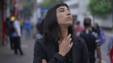 Endişeli genç bir İspanyol kadın sokakta endişeli ve endişeli duruyor. İş kadını Latin, endişe ve meşguliyet hissederken bekliyor.