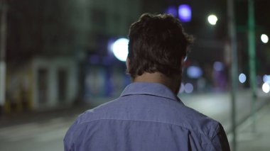 Düşünceli, düşünceli bir adamın sırtında. Gece kaldırımda yürürken.