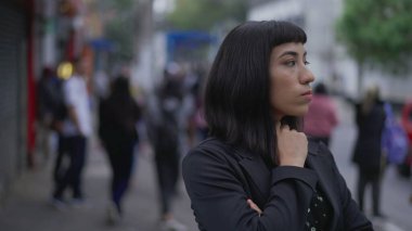 Endişeli genç bir İspanyol kadın sokakta endişeli ve endişeli duruyor. İş kadını Latin, endişe ve meşguliyet hissederken bekliyor.