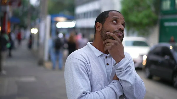 一个沉思的年轻黑人男子站在城市街道上 一个深思熟虑的非裔美国人站在人行道上思考的画像 — 图库照片