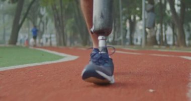 Engelli bir sporcunun protez bacakla dışarıda dolaşması ön planda. Engelli bir erkek