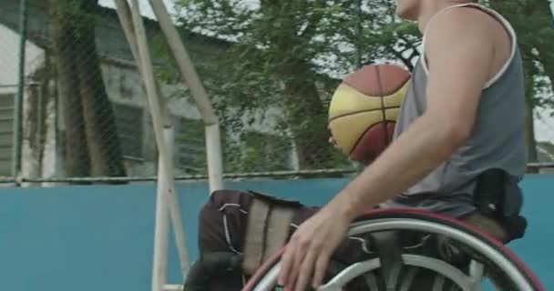 車いす投げのプロの障害者バスケットボール選手の1人がネットと得点にボールを投げる 障害のスコアポイントを持つ南アメリカの男性選手 — ストック動画