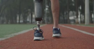 Koşu yolunda yürüyen protez bacaklı engelli bir sporcunun arka planı
