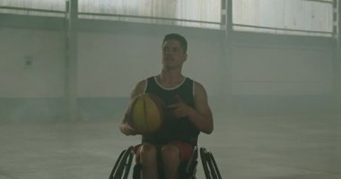 Bir engelli atlet basketbol topu çeviriyor. Belden aşağısı felçli bir Brezilyalı içeride top çeviriyor.
