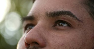 Hispanik bir adam gökyüzüne bakıyor, düşüncelere dalmış, Latinlerin mutlulukta gözleri açıp kapanıyor.