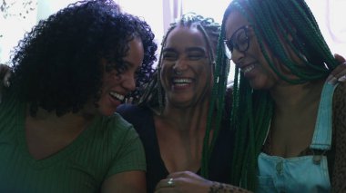 Mutlu kadınlar gülüyor ve gülümsüyor. Üç siyahi Afrikalı Amerikalı kız arkadaş sarılıyorlar.