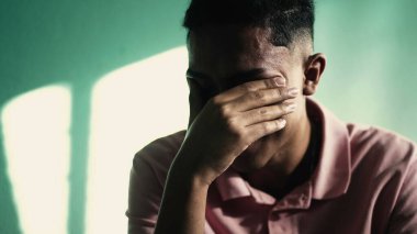Depresyondaki genç adam yüzünü eliyle kapatıyor ve ANXIETY hissediyor. TRAUMA 'yı hatırlayan olumsuz duyguları olan acı çeken kişi.