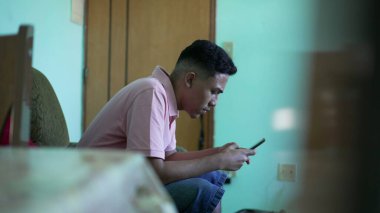 İspanyol bir adam kanepede oturuyor ve telefon kullanıyor. Akıllı telefon tutan bir Latin.