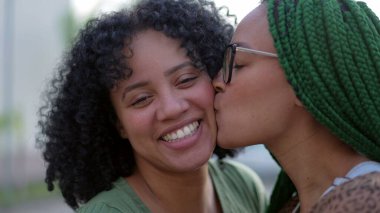 Sevgi ve şefkat gösteren iki siyah kız kardeş. Afro-Amerikan kardeş yanaktan öpüşüyor. Mutlu İspanyol Güney Amerika halkı umursuyor