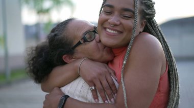 Brezilyalı yetişkin kız, büyük anneye sarılıp sevgi ve şefkat gösteriyor. Yaşlı bir bayanı kucaklayan şefkatli siyah bir kadın.