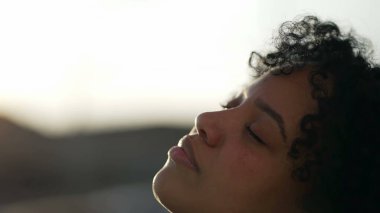 Meditasyoncu Afro-Amerikan derin düşüncelere dalarak gözlerini kapatıyor. Kaygısız siyah bir kız gökyüzüne gözlerini açıyor yakın çekim yüzü