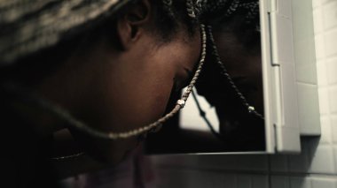 Depresyonda olan siyah bir kadın tuvalet aynasına yaslanıyor ve akıl hastalığı çekiyor.