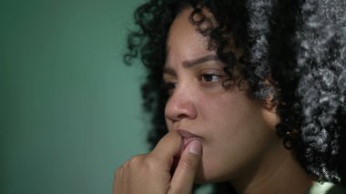 Afro-Amerikalı düşünceli kadın. Düşünceli siyah bir kız duvara yaslanıyor çene kısmında çözümü düşünüyor.