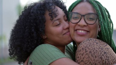Sevgi ve şefkat gösteren iki siyah kız kardeş. Afro-Amerikan kardeş yanaktan öpüşüyor. Mutlu İspanyol Güney Amerika halkı umursuyor