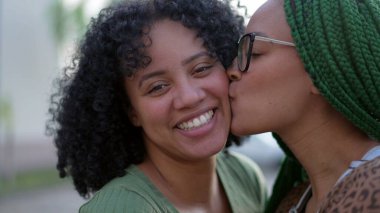 Sevgi ve şefkat gösteren iki siyah kız kardeş. Afro-Amerikan kardeş yanaktan öpüşüyor. Mutlu İspanyol Güney Amerika halkı umursuyor