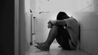 Depresyondaki genç adam, tek renkli zor zamanlarda mutfak zemininde otururken yüzünü kapatıyor. Akli dengesi bozuk bir erkek. Stres negatif duygular