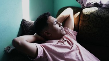 Düşünceli Latin bir adam kanepede uzanmış, dinleniyor ve hayal kuruyor. Düşünceli biri.