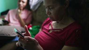 Evde telefonu tutan İspanyol asıllı son sınıf öğrencisi. Güney Amerikalı yaşlı bir kadın cep telefonu ekranına bakıyor.