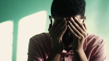 Depresyondaki genç adam yüzünü eliyle kapatıyor ve ANXIETY hissediyor. TRAUMA 'yı hatırlayan olumsuz duyguları olan acı çeken kişi.