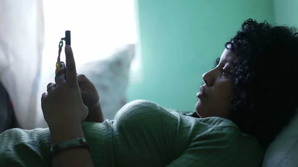 Een Zwarte Vrouw Liggend Bed Staren Naar Smartphone Scherm Thuis — Stockfoto