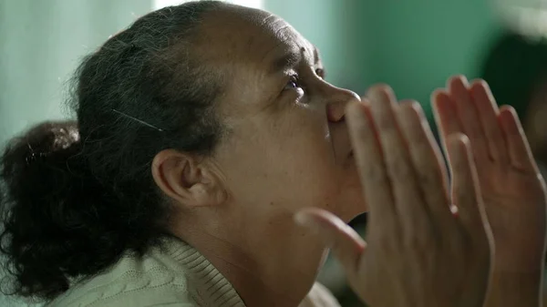 Religious Hispanic older woman praying to God. Spiritual Brazilian senior lady prays to divinity looking at sky in prayer